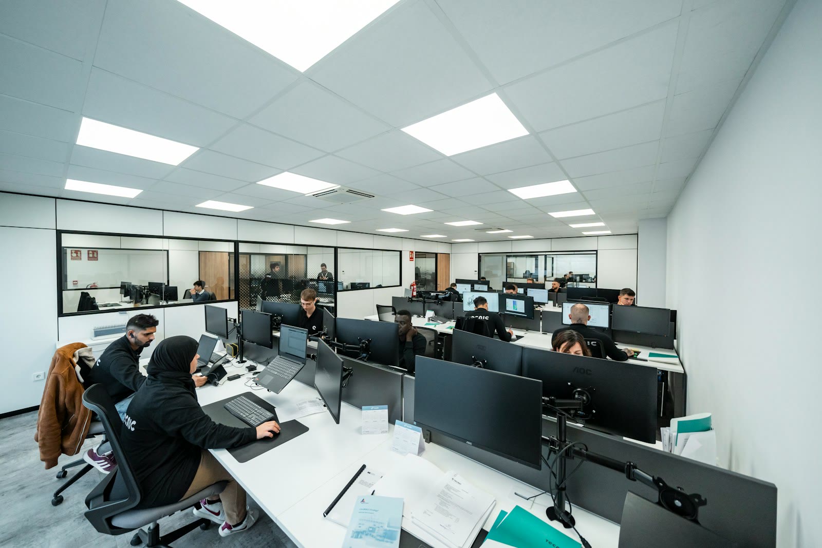 L'équipe Teleqo au travail à ses postes, plusieurs membres portant un casque devant leurs écrans.